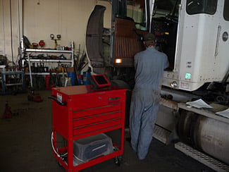 technition diagnosing truck back view